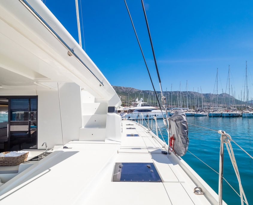 Luxury sailing yacht at marina with clear blue sky and calm waters.