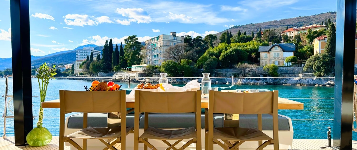 Luxury Sunreef 80 sailing yacht on the water with scenic coastal backdrop.