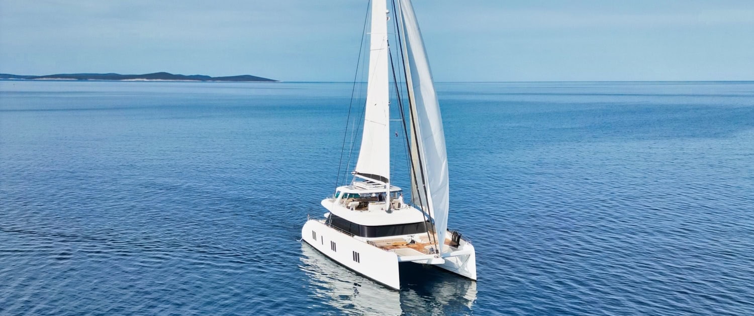 Luxury Sunreef 80 sailing yacht on calm blue waters.
