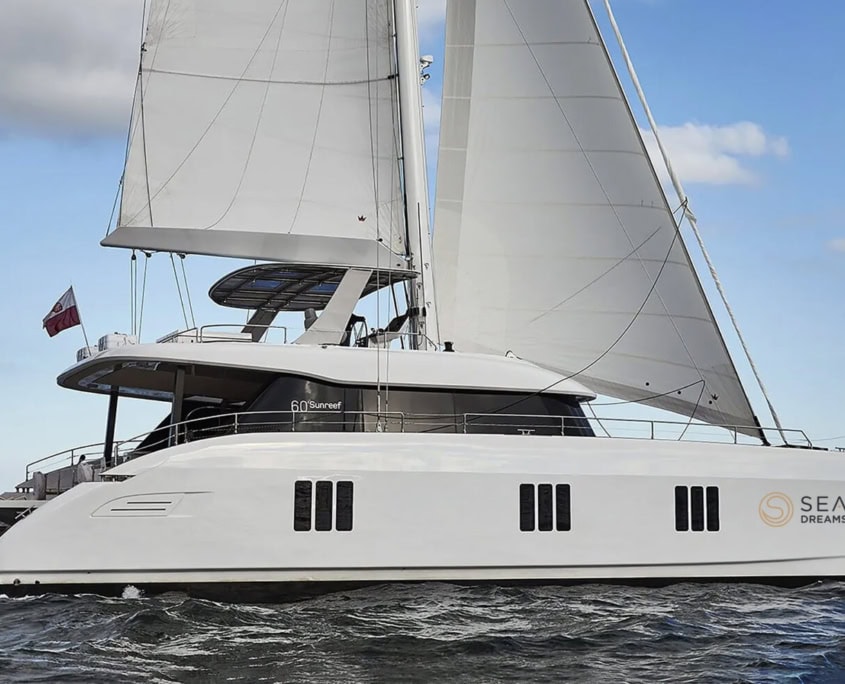 Luxury Sunreef 60 sailing catamaran on ocean, perfect for sailing vacations.