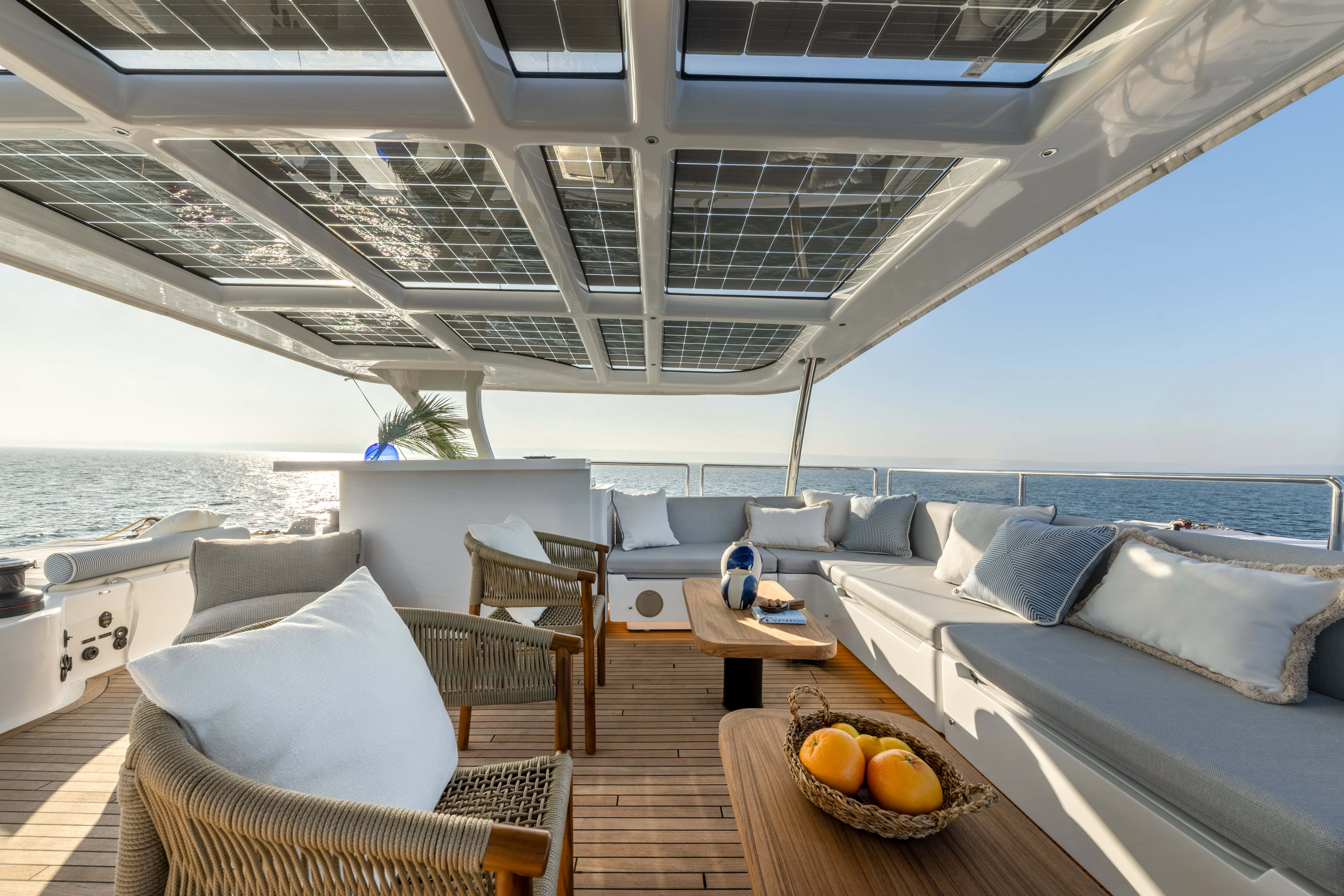 Sun deck with cozy seating and solar panels on Ocean Sailing House yacht.